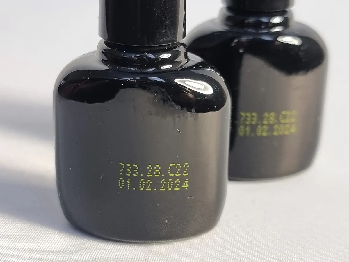 Маркировка жёлтыми чернилами на чёрной глянцевом флаконе принтером Saturn K750