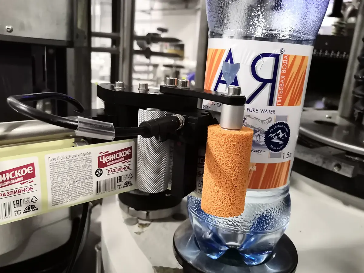 Аппликатор Novexx XLS наносит этикетку на бутылку с питьевой водой — пример боковой маркировки продукции в Казахстане