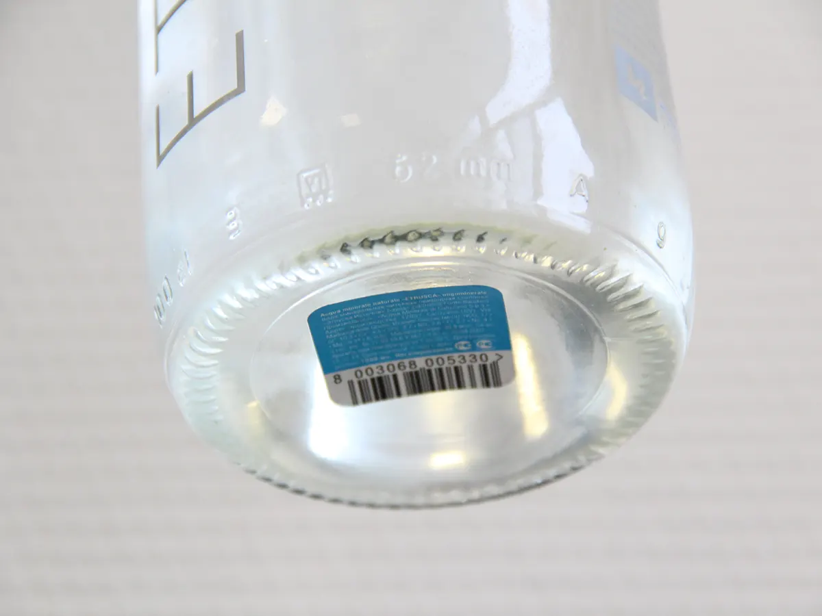 Novexx — нижнее нанесение этикетки на стеклянную бутылку на конвейерной линии